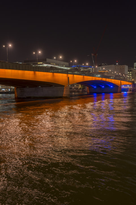 The lights of London Bridge reflected in the River Thames at night.
